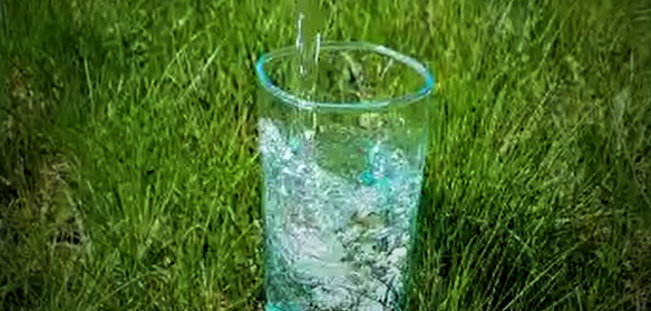 Glas mit Wasser auf der Wiese